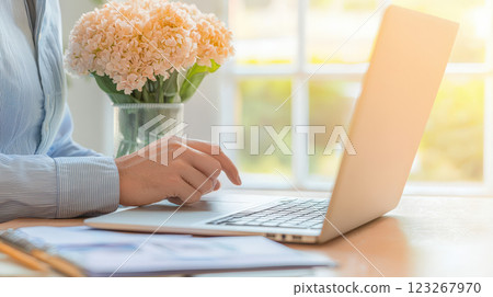 business professional working on laptop with flowers nearby, creating productive atmosphere 123267970