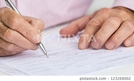 Close up of hands writing on document with pen, showcasing focus and diligence 123268002