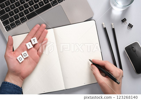 Concept of motivation and productivity with a notepad and Do It caption. Hand holding pen over empty notepad on desktop background. Copyspace Concept of motivation and productivity with a notepad and Do It caption. Hand holding pen over empty notepad on desktop background. Copyspace 123268140