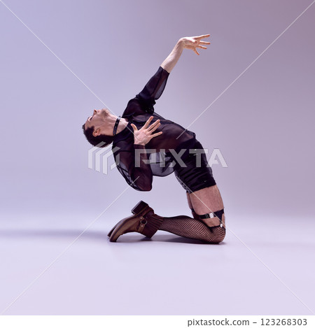 Dramatic dancer arching backward with extended arm, wearing dark Avantgarde style outfit against gradient background. 123268303