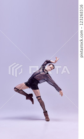 Artistic man lifting leg dramatically in bold leopard print outfit while exuding intense energy against white studio background. Artistic man lifting leg dramatically in bold leopard print outfit while exuding intense energy against white studio background. 123268316