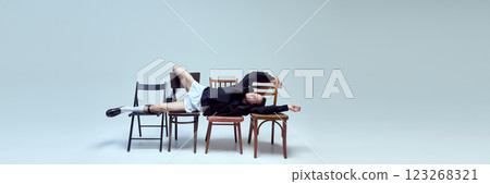 Banner. Stylish young man reclining across chairs with relaxed pose and playful confidence against white background with copy space. Banner. Stylish young man reclining across chairs with relaxed pose and playful confidence against white background with copy space. 123268321