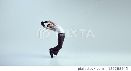 Young male dancer curving body with striking elegance and artistic fluidity through dance moves against white studio background. 123268345