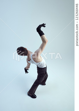 Aerial view of young man, dressed high-fashion outfit, moving elegantly raising hands against gradient background, highlight luxury style. Aerial view of young man, dressed high-fashion outfit, moving elegantly raising hands against gradient background, highlight luxury style. 123268446