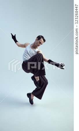Young man dressed high-fashion outfit, showcasing dynamic fashion essence with bold elegance, redefining movement and style against gradient background. Young man dressed high-fashion outfit, showcasing dynamic fashion essence with bold elegance, redefining movement and style against gradient background. 123268447