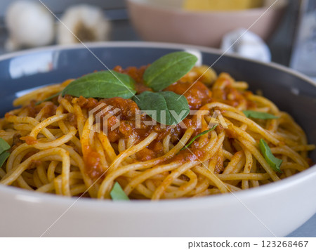 Balanesi pasta, coated in a rich tomato sauce and garnished with vibrant fresh basil leaves, beautifully presented in a bowl, inviting enjoyment for any meal occasion 123268467