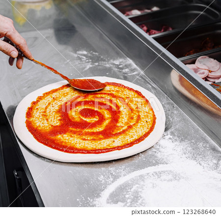 Preparing a pizza with sauce in an Italian kitchen space 123268640