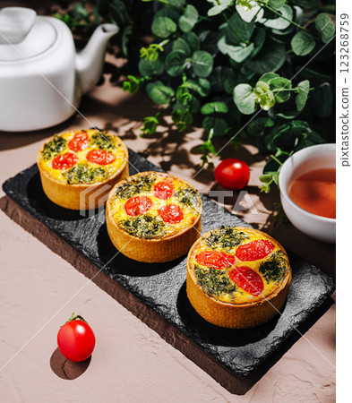 Delicious savory tarts with vegetables served on a slate platter 123268759