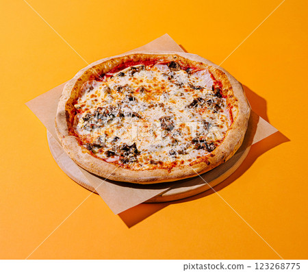 Freshly baked pizza with toppings on vibrant orange backdrop 123268775