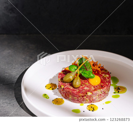 Beef tartare garnished with egg and vegetables in modern setting 123268873
