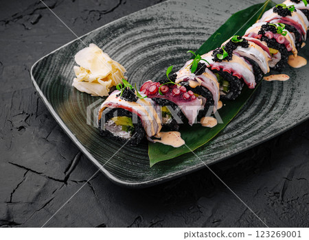 Fresh sushi roll with colorful toppings served on a textured plate Fresh sushi roll with colorful toppings served on a textured plate 123269001