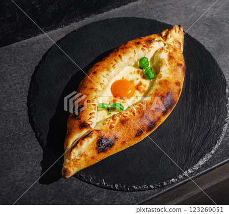 Delicious freshly baked khachapuri served on a black stone plate 123269051