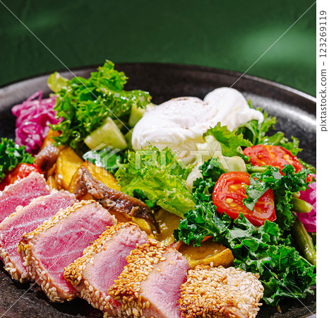 Fresh salad with poached egg and seared tuna on a dark plate 123269119