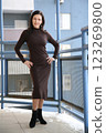 Brunette woman 51 years old posing in a brown dress and black boots on a balcony in winter 123269800