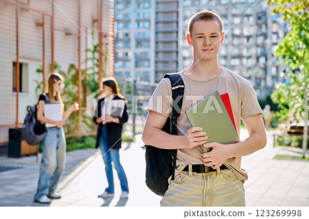 Portrait of college student guy looking at camera outdoor near educational building 123269998