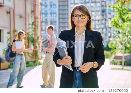 Portrait woman teacher looking at camera, outdoor, group of students background 123270000