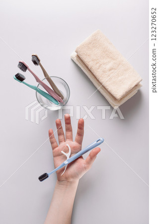 Toothbrush and dental floss in hand against background of toiletries top and vertical view 123270652