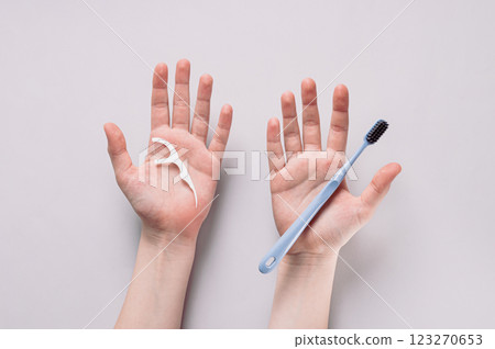 Toothbrush and dental floss on palms, alternative to brushing teeth top view 123270653