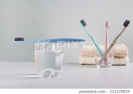 Toothbrush on a glass of water, disposable dental floss in the bathroom Toothbrush on a glass of water, disposable dental floss in the bathroom 123270654