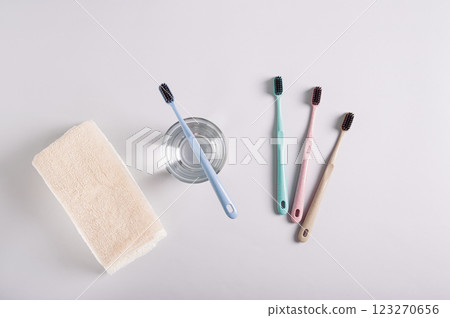 Toothbrush on glass with water, other toothbrushes and towel on gray background 123270656