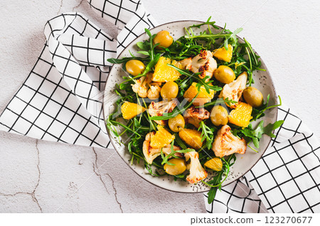 Close up of vegetarian salad with cauliflower, orange, arugula and olives on a plate top view Close up of vegetarian salad with cauliflower, orange, arugula and olives on a plate top view 123270677