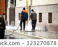 The municipal service washes the streets. An employee washes the street from dirt with high pressure. Street cleaning. Spring. 123270878