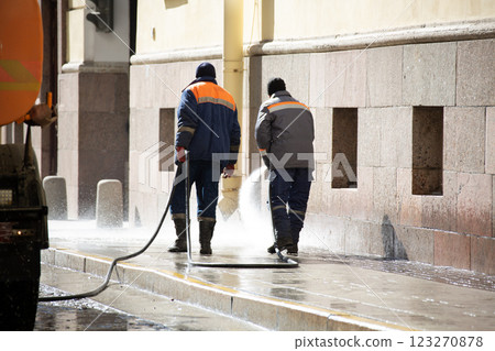 The municipal service washes the streets. An employee washes the street from dirt with high pressure. Street cleaning. Spring. The municipal service washes the streets. An employee washes the street from dirt with high pressure. Street cleaning. Spring. 123270878