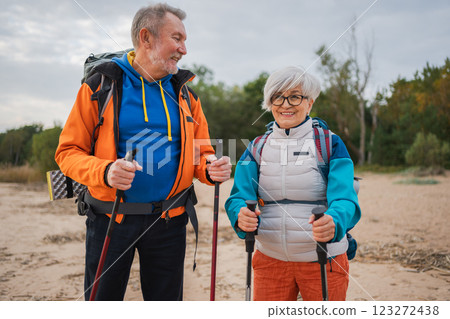 Hiking tourism adventure. Senior couple man woman enjoying outdoor recreation hiking on beach. Happy old people backpackers hikers enjoy walking hike trekking tourism active vacation beauty of nature Hiking tourism adventure. Senior couple man woman enjoying outdoor recreation hiking on beach. Happy old people backpackers hikers enjoy walking hike trekking tourism active vacation beauty of nature 123272438
