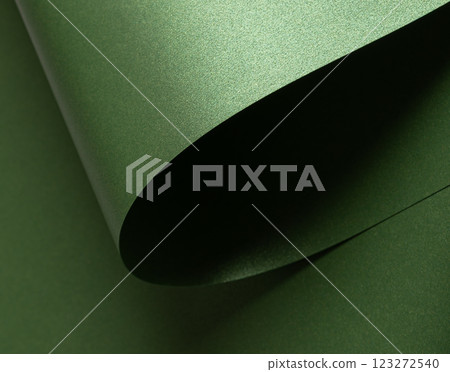 Emerald green paper background with a pearlescent, glossy texture and shimmering wavy edges. Deep 123272540