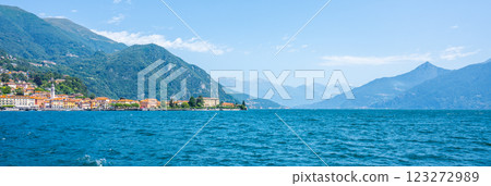 Visitors enjoy the serene beauty of Lake Como, surrounded by majestic mountains and charming villages. The clear blue waters reflect the vibrant landscape, evoking a sense of peace and relaxation. 123272989
