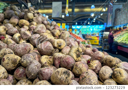 A large pile of freshly harvested beets with dirt still on them is displayed prominently in the produce section of a grocery store 123273229