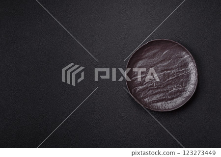 Empty black ceramic plate on a dark concrete background Empty black ceramic plate on a dark concrete background 123273449