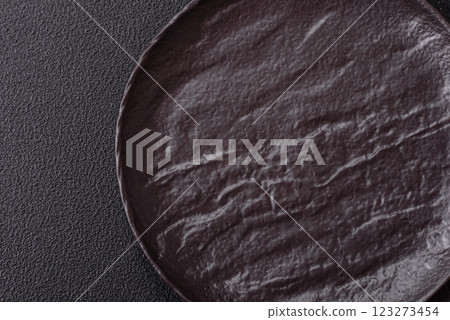 Empty black ceramic plate on a dark concrete background Empty black ceramic plate on a dark concrete background 123273454
