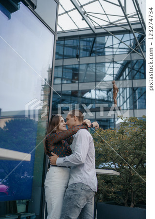 Romantic scene of a couple of lovers sitting at a table outside a cafe. The man and woman are kissing gently, holding hands, which emphasizes their closeness and intimacy. 123274734