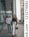 Romantic couple embracing and sharing a kiss in an urban setting. Young stylish man and woman in trendy outfits enjoying a moment of love on a city sidewalk. Modern architecture in the background. 123274882