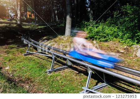 Person motion blurred enjoy have fun riding fast alpine roller coaster cart together at Harz nature park on sunny holidays summer day. Children summer outdoors travel active sports adventure Person motion blurred enjoy have fun riding fast alpine roller coaster cart together at Harz nature park on sunny holidays summer day. Children summer outdoors travel active sports adventure 123275953