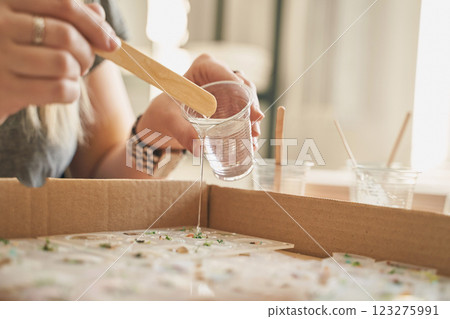 Hands creating resin art: female, caucasian, adult crafting with epoxy resin 123275991
