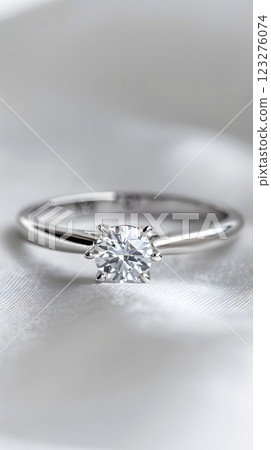 A beautiful solitaire diamond ring, featuring a sparkling gem on a sleek metal band, elegantly showcased on a smooth white surface, perfect for an engagement or wedding proposal 123276074