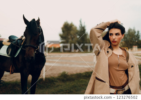 Cowgirl in brown clothes with her horse at outdoors ranch 123276502