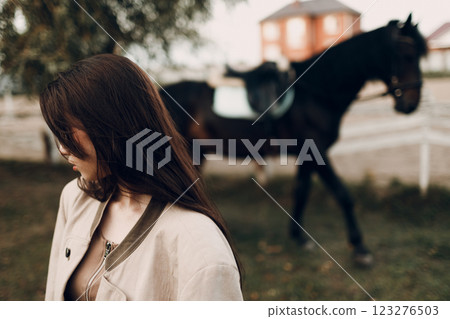 Cowgirl in brown clothes with her horse at outdoors ranch 123276503