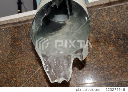 Icy drainpipe with frozen water forming delicate icicles during winter season in urban setting Icy drainpipe with frozen water forming delicate icicles during winter season in urban setting 123276646