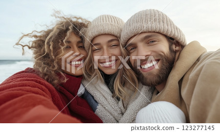 Friends enjoy a joyful moment together on a chilly beach day, celebrating friendship and warmth against the backdrop of the ocean. Generative AI 123277145