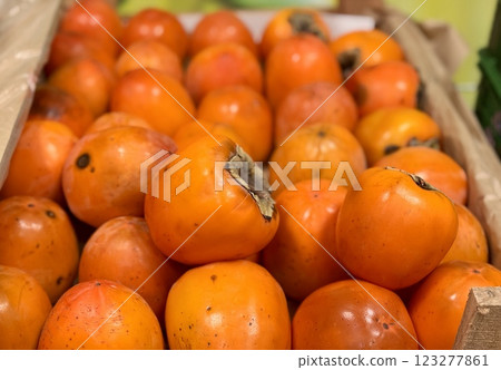 A pile of ripe juicy orange persimmons in a box, on sale at a supermarket vegetable stand, showcases organic, vegetarian and healthy food. Close-up. A pile of ripe juicy orange persimmons in a box, on sale at a supermarket vegetable stand, showcases organic, vegetarian and healthy food. Close-up. 123277861
