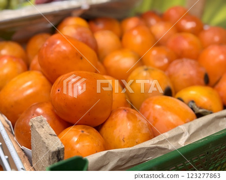 A pile of ripe juicy orange persimmons in a box, on sale at a supermarket vegetable stand, showcases organic, vegetarian and healthy food. Close-up. A pile of ripe juicy orange persimmons in a box, on sale at a supermarket vegetable stand, showcases organic, vegetarian and healthy food. Close-up. 123277863