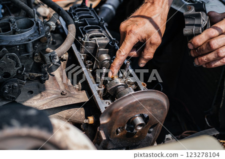 A worker repairs the cylinder head of an automobile engine. Oil removal valve. Car repairs. Car service A worker repairs the cylinder head of an automobile engine. Oil removal valve. Car repairs. Car service 123278104