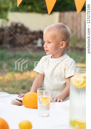 A boy in a yellow T-shirt and with yellow oranges looks away on a warm summer day. A boy in a yellow T-shirt and with yellow oranges looks away on a warm summer day. 123278166