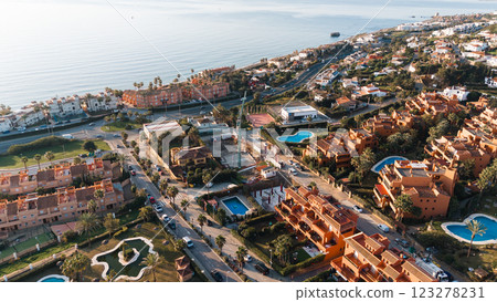Aerial view of coastal town with mediterranean architecture and swimming pools at sunset Aerial view of coastal town with mediterranean architecture and swimming pools at sunset 123278231