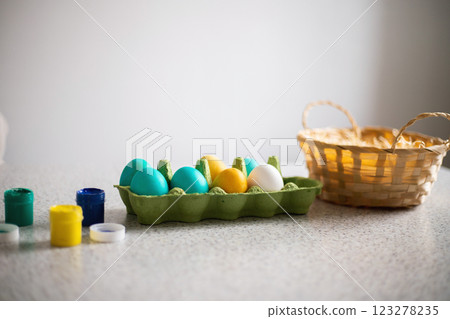 Ready-painted eggs stand on the table with paints and a wicker basket on a sunny day. Easter 123278235