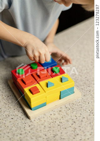 A child plays an educational puzzle toy made of environmentally friendly wood material 123278287