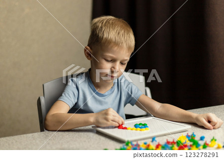 A focused child plays educational colorful puzzles. The concept of early development 123278291